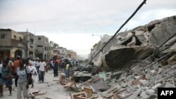 Haiti -- Haitians walk past damaged buildings in Port-au-Prince after a huge earthquake measuring 7.0, 12Jan2010