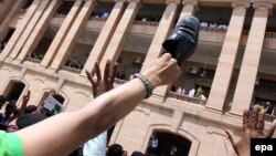 Nägileligini aýan etmek üçin köwüşini eline alyp, ýokary galdyran adam