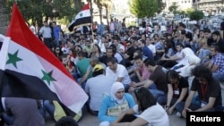 Syrian youths attend a sit-in in Damascus on June 29 to honor victims of the recent violence.