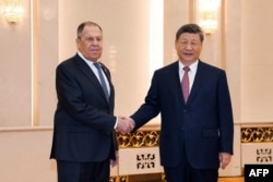 Russian Foreign Minister Sergei Lavrov (left) shakes hands with Chinese President Xi Jinping in Beijing on April 15.