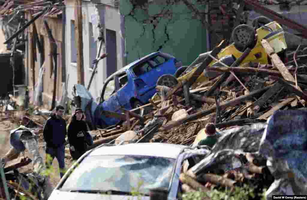 Njerëzit ecin mes rrënojave të shtëpive dhe automjeteve të shkatërruara, pas tornados së rrallë që goditi dhe shkatërroi pjesë të disa qytezave, në fshatin Mikulçice.