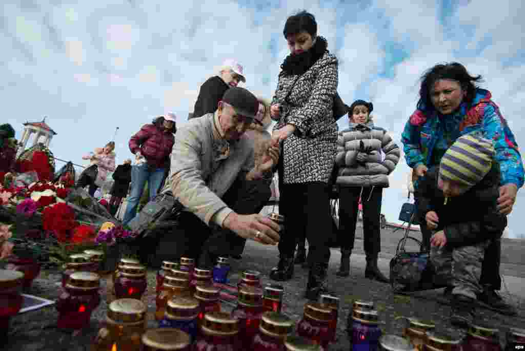 Residents of Sochi place candles and lay flowers &nbsp;at an impromptu shrine paying tribute to the victims of a plane that crashed minutes after taking off from the Black Sea city on December 25, killing all 92 people on board. (epa/Yevgeny Reutov)&nbsp;