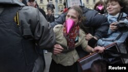 Russian police detain an opposition activist holding a portrait of President Vladimir Putin during a protest on Putin's birthday in Moscow on October 7.