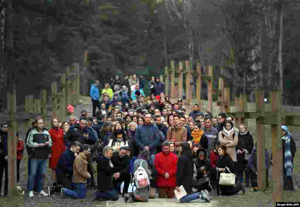 Local residents pray next to the line of wooden crosses marking the Soviet-era mass grave site in Kuropaty, in the Belarusian capital, Minsk, on April 4. (AP/Sergei Grits)