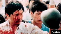 A blood-covered protester holds a Chinese soldier's helmet following violent clashes with military forces during the 1989 pro-democracy demonstrations in Beijing's Tiananmen Square in this June 4, 1989, photo.