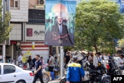 People walk past a banner featuring a picture of the late Hamas political leader Ismail Haniyeh, who was killed in an attack in Tehran.