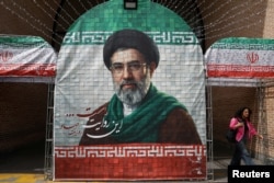 A woman walks next to a banner with a picture of Iranian Supreme Leader Mojtaba Khamenei in Tehran on May 8.