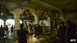 Afghan security personel inspect the site of a suicide bomb attack at a Shi'ite mosque in Herat on August .