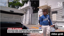 Молоді люди в одязі з символікою молодіжного крила путінської партії «Единая Россия» розвозять воду маломобільним жителям Євпаторії. Скріншот відео каналу «Крым 24», 17 липня 2026 року