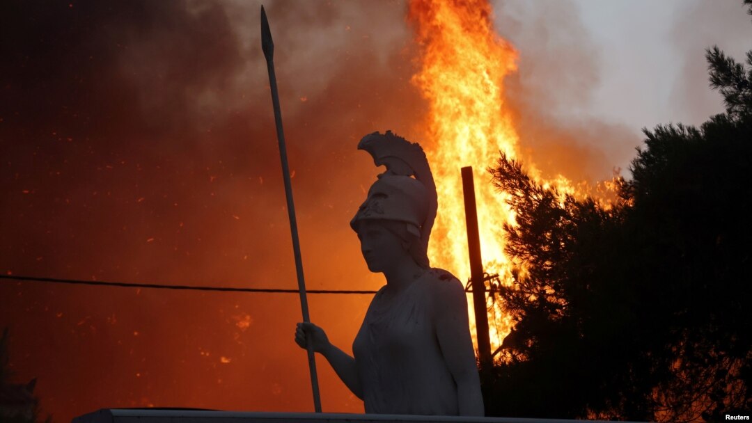 O statuie a zeiței Atena și flăcările din suburbia Varibombi a capitalei Greciei. 3 august 2021.