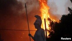 Kip boginje Atene vidi se kako gori u požaru u predgrađu Varimpompi sjeverno od Atine, Grčka, 3. augusta 2021.