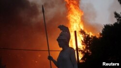 O statuie a zeiței Athena, surprinsă în vecinătatea incendiilor din suburbia Varympompi, la nord de Atena, Grecia, 3 august 2021.