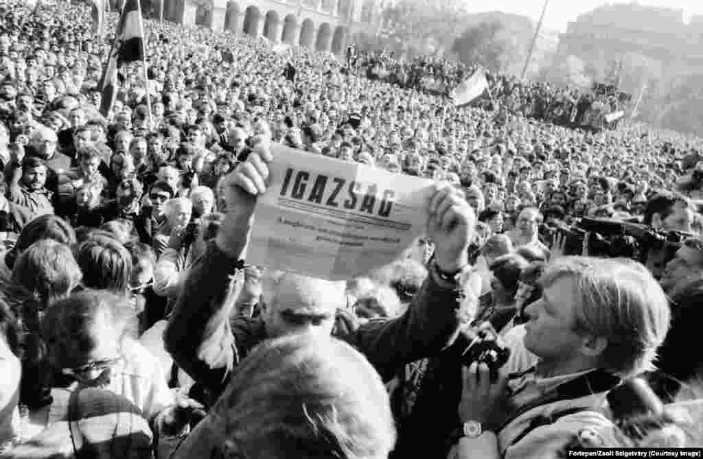 Un bărbat ține în mână un ziar ce anunță că Ungaria a devenit o republică democratică, la 23 octombrie 1989. Titlul declară acea zi drept o &bdquo;victorie așteptată, dar în niciun caz întârziată&rdquo;. Parlamentul Ungariei a aprobat în scurt timp modificarea constituției țării, deschizând astfel calea către alegeri libere. Președintele în exercițiu al țării, Matyas Szuros, a anunțat în fața unei mulțimi de mii de oameni, adunate la parlament: &bdquo;Declar solemn că, începând de astăzi, 23 octombrie 1989, Ungaria este o republică și se numește Republica Ungară&rdquo;.