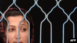 A prisoner looks out from a fenced window at the Female Detention Center in Kabul.