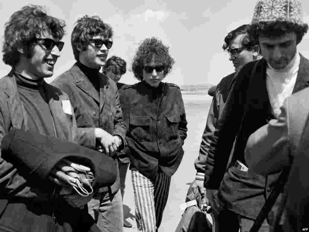 Dylan arrives at Le Bourget airport in France on May 22, 1966, surrounded by his band.