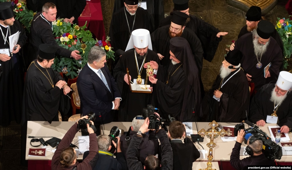 Учасники Об’єднавчого собору вітають новообраного главу ПЦУ митрополита Київського та всієї України Епіфанія. Київ, 15 грудня 2018 року. Тоді всі звернули увагу, що Філарет (на фото справа) прийшов в чорному клобуці, а не митрі і це було сприйнято як знак скромності і смиренності