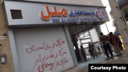 A bank branch attacked in Shiraz, Iran. Slogans written in red say, "Death to Khamenei, Death to Rouhani". November 17, 2019
