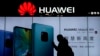 CHINA - A woman browses her smartphone as she walks by a Huawei store at a shopping mall in Beijing, December 11, 2018.
