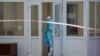Медик Калинівської лікарні у повному захисному костюмі зачиняє двері корпусу №1, який зараз знаходиться на повному карантині