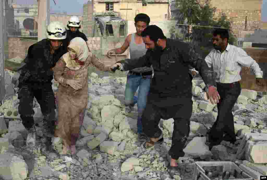 Syrian rescue workers and residents help an injured woman following a reported air strike by government forces on a rebel-held neighborhood in Aleppo. (AFP/Thaer Mohammed)