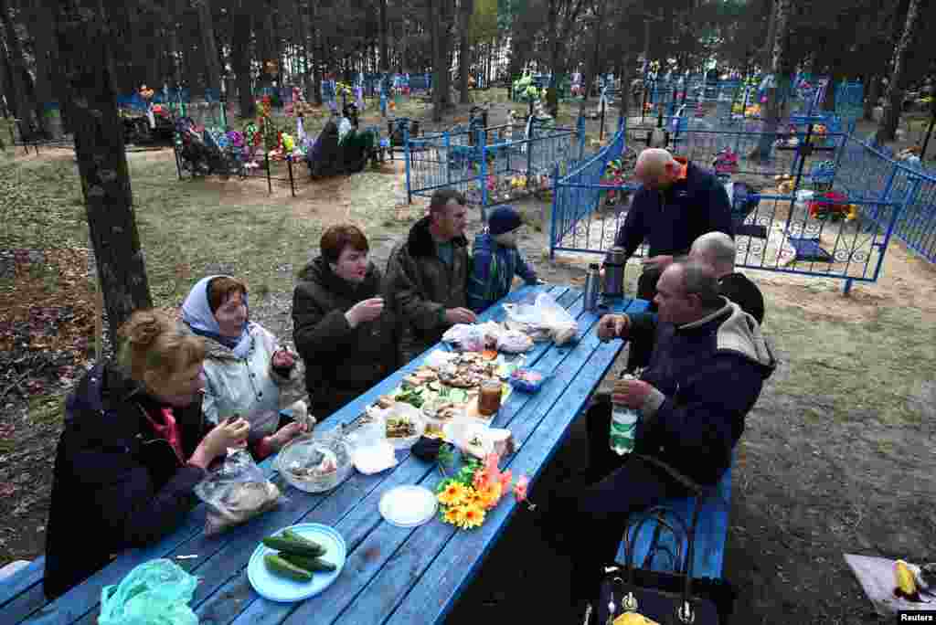 Людзі п&#39;юць і ядуць на могілках у пакінутай вёсцы Ломыш непадалёк ад зоны адчужэння вакол Чарнобыльскай АЭС у Беларусі напярэдадні Радаўніцы.