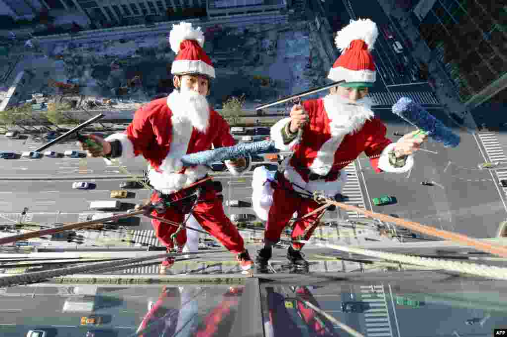 Clad in Santa Claus costumes, workers clean windows some 55 meters above the ground outside a hotel in Tokyo. (AFP/Toru Yamanaka)