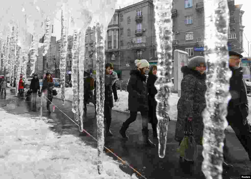 People walk past icicles hanging from the roof of a building in a street in central Kyiv on January 13 (Reuters/Gleb Garanich).&nbsp;