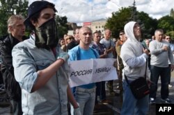 A protester holds a sign reading "Russia is a killer."