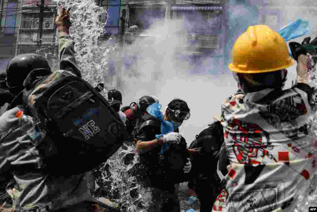 Protesters throw water in an effort to control tear gas fired by police during a demonstration against the military coup in Yangon on March 2, 2021.