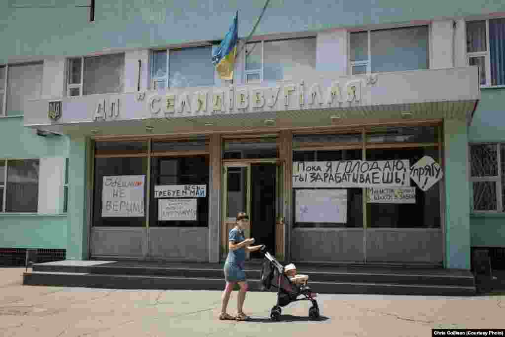 Signs on a mine administration building criticize the Ukrainian government for failing to pay salaries to coal miners.