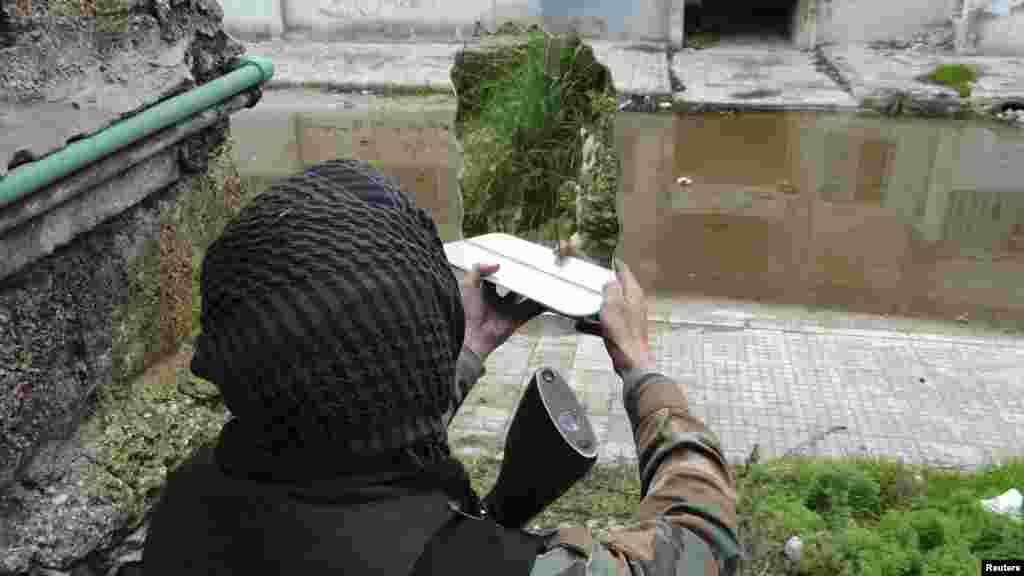 A Free Syrian Army fighter uses a mirror to locate the position of a pro-government sniper in Aleppo&#39;s al-Amereya district. (Reuters/Aaref Hretani)