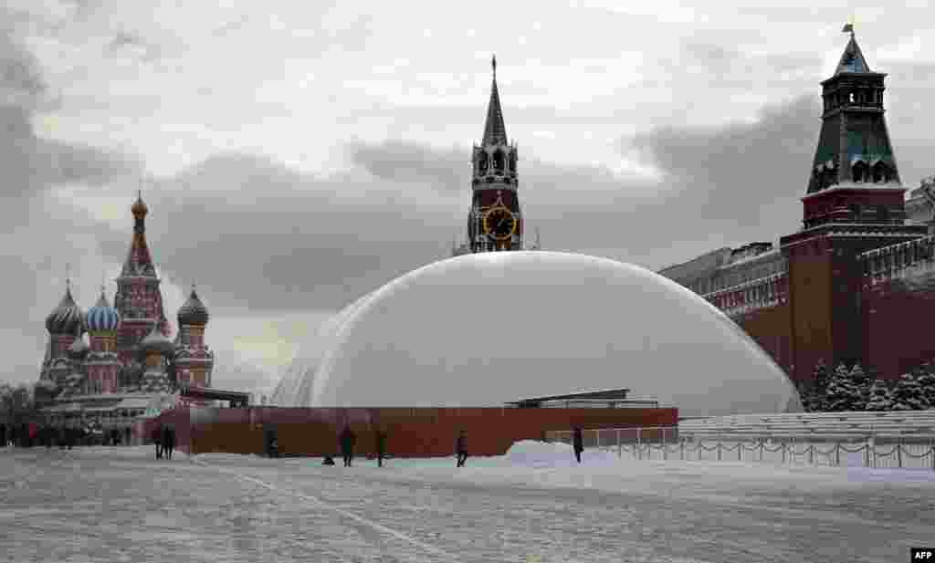 People stand near a huge temporary dome covering the mausoleum of Soviet state founder Vladimir Lenin on Red Square in Moscow. The dome keeps temperatures inside warmer and allows repair works on the mausoleum to continue to meet an end-of-April deadline. (AFP/Alexander Nemenov)