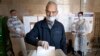 A man casts his ballot at a polling station in Moscow in July 2020 as observers look on.