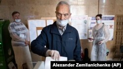 A man casts his ballot at a polling station in Moscow in July 2020 as observers look on.