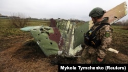 Un soldat ucrainean inspectează resturile unui avion Sukhoi Su-25, doborât în regiunea Kievului, 21 aprilie 2022.