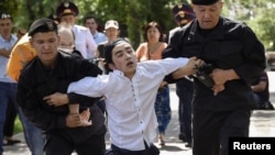 Kazakh police officers detain an opposition supporter attempting to stage a protest rally in Almaty on June 23. 