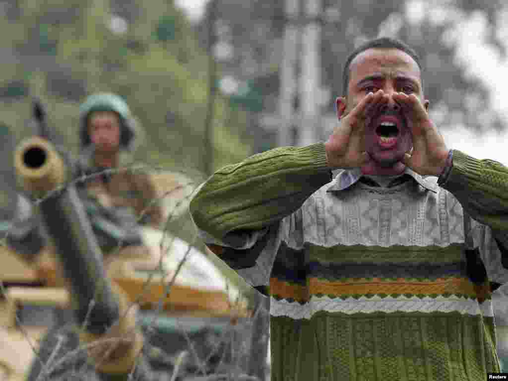 An opposition supporter makes a call for prayer near a tank in front of the presidential palace in Cairo on February 11.