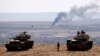 Turkish tanks near the Syrian border look on as smoke rises from the besieged city of Kobani on October 8.