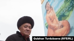 Турдаалы Кожоналиев на фоне портрета убитой дочери Бурулай Турдаалы кызы на здании медколледжа в Бишкеке.