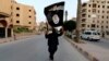 A member loyal to the Islamic State in Iraq and the Levant (ISIL) waves an ISIL flag in Raqqa, Iraq.