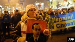 Женщина держит портрет Степана Бандеры во время марша в Киеве. 1 января 2014 года.