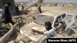 Pakistan -- Survivors clear the debris of destroyed houses in the earthquake-devastated district of Awaran, Balochistan province, September 25, 2013