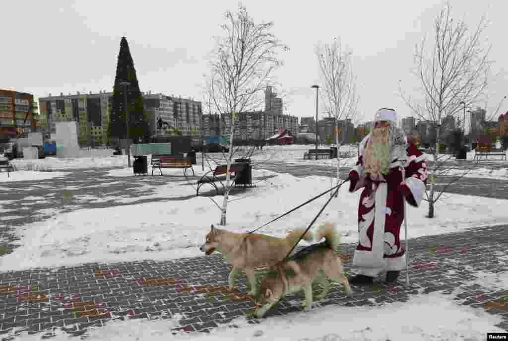 Muškarac obučen u Djeda Mraza šeta sa sibirskim haskijem na tradicionalnom božićnom sajmu u Krasnojarsku, Sibir. (Reuters/Ilya Naymushin)