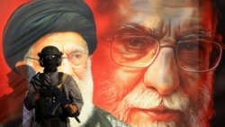 A member of Kataib Sayyid al-Shuhada stands guard in front of a mural depicting Iran's late Supreme leader Ayatollah Ali Khamenei during a rally in support of Iran, in Baghdad on June 19.