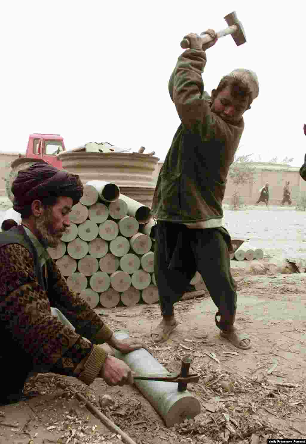 Men in northern Afghanistan hack up old Soviet shell cartridges to melt into household objects. Although open warfare stopped in most of the country after the Taliban seized control, the group's rigid enforcement of Islamic law and tribal traditions perpetuated the suffering of many ordinary Afghans.