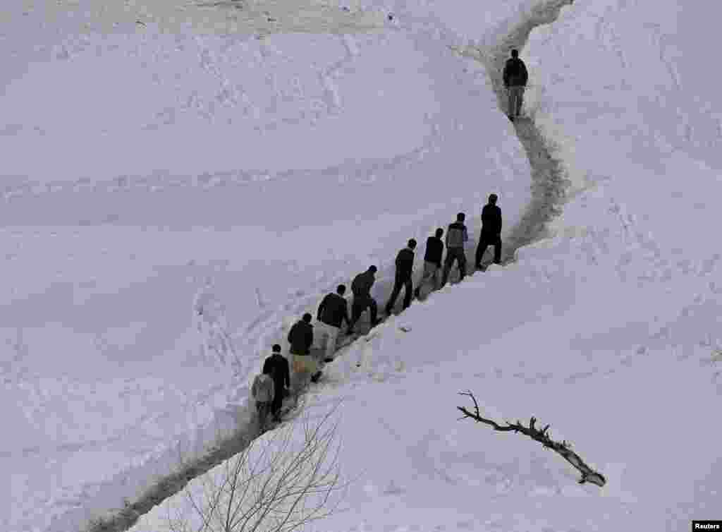 Survivors of an avalanche walk in the Abdullah Khil village of the Dara district of Panjshir Province in Afghanistan. (Reuters/​Omar Sobhani)