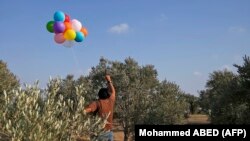 در این عکسی که خبرگزاری فرانسه منتشر کرده فردی در غزه در حال فرستادن بادکنکهای قابل اشتعال به جنوب اسرائیل است