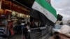 Boy eats, next to the flag adopted by the new Syrian rulers, in Damascus