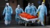 Мэдыцынскія работнікі вывозяць цела памерлага чалавека з мэдыцынскага цэнтру ў раёне Бруклін, Нью-Ёрк. ЗША, 2 красавіка 2020 году