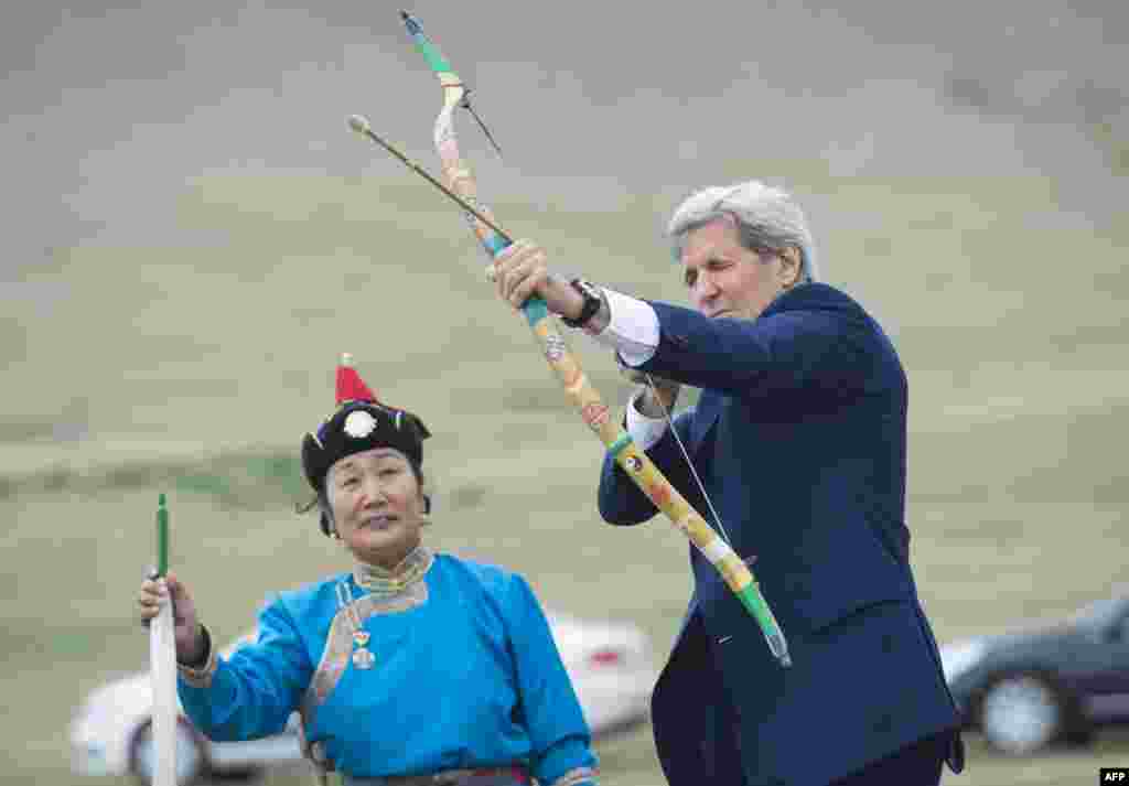 On a trip to Mongolia, U.S. Secretary of State John Kerry shoots a traditional bow and arrow in Ulan Bator. (AFP)